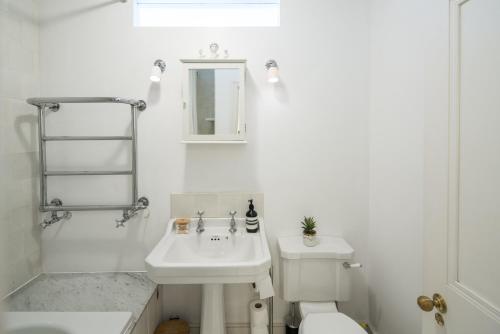 a white bathroom with a sink and a toilet at 1min to Portobello Road Market! Stylish Cosy 2 Bed Flat in the Heart of Nottinghill in London