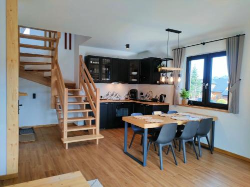 eine Küche und ein Esszimmer mit einem Holztisch und Stühlen in der Unterkunft Domki Hygge Tatra Luxury Chalet in Murzasichle