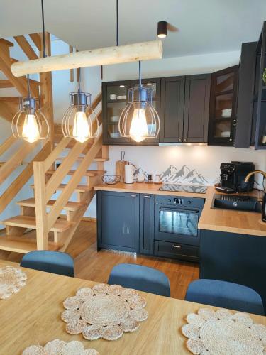 a kitchen with black cabinets and a table with blue chairs at Domki Hygge Tatra Luxury Chalet in Murzasichle