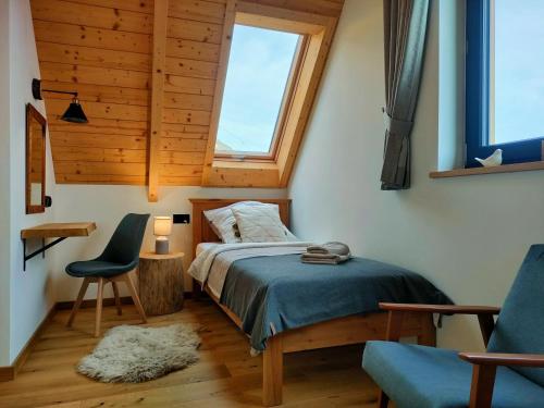 a bedroom with a bed and a chair and a window at Domki Hygge Tatra Luxury Chalet in Murzasichle