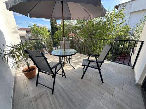 eine Terrasse mit Tisch und Stühlen und einem Sonnenschirm in der Unterkunft Three Palms Guest House in Tbilisi City