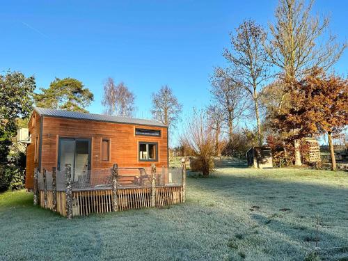 a small wooden cabin with a fence in a field at Joy Tiny House Perche in Madeleine