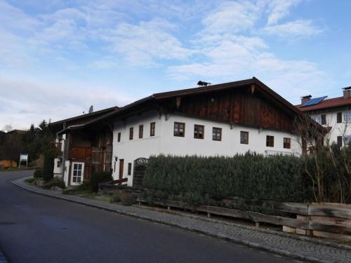 a white house with a wooden roof on a street at Ferienhaus Judie in Lechbruck