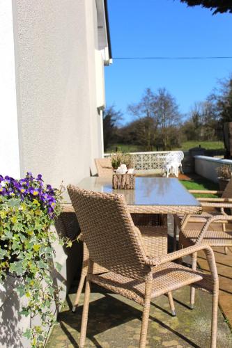 a patio with two chairs and a table and a table and some flowers at Heather Cottage and Shepherds Hut in Knock