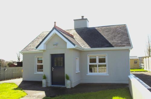 una pequeña casa blanca con una puerta azul en Heather Cottage and Shepherds Hut, en Knock