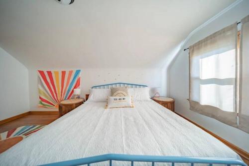 1 dormitorio con 1 cama blanca grande y ventana en The House Hotels - 12th Street, en Cuyahoga Falls