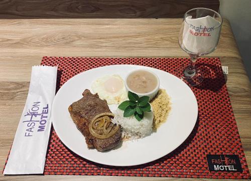 un plato de comida con arroz y carne y una copa de vino en Motel Fashion ABC 5, en Santo André