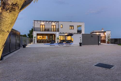 une grande maison blanche avec deux bancs devant elle dans l'établissement Ferienhaus für 14 Personen in Loborika, Istrien Südküste von Istrien, à Loborika