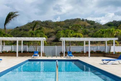 Point的住宿－SeaJam Vacation Home between Negril & Montego Bay，一个带蓝色椅子和围栏的游泳池
