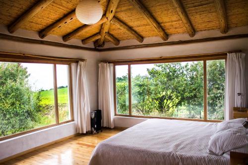 Schlafzimmer mit zwei großen Fenstern und einem Bett in der Unterkunft Confortable casa de campo en el Atacazo, muy cerca de Quito in Tambillo