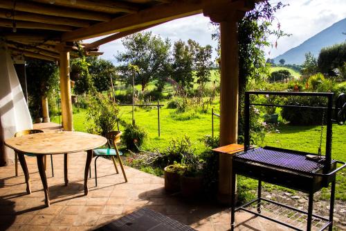 eine Terrasse mit einem Tisch und Blick auf ein Feld in der Unterkunft Confortable casa de campo en el Atacazo, muy cerca de Quito in Tambillo