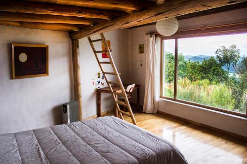ein Schlafzimmer mit einer Leiter und einem großen Fenster in der Unterkunft Confortable casa de campo en el Atacazo, muy cerca de Quito in Tambillo