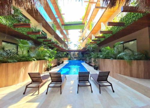 トゥルムにあるLuxury Condo in the Heart of Tulum!!の椅子と植物のある建物内のスイミングプール