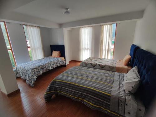 two beds in a room with windows at Casa edad dorada in Calca