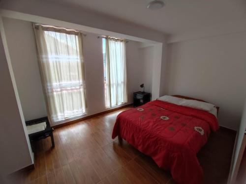 a bedroom with a red bed and two windows at Casa edad dorada in Calca