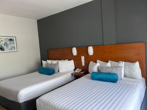 two beds in a hotel room with blue pillows at Days Inn by Wyndham Minatitlan in Minatitlán