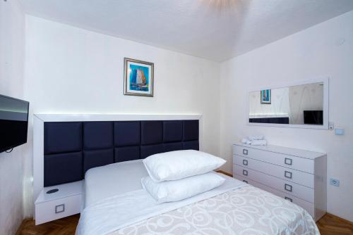a bedroom with a bed with a black headboard and a dresser at M&M Pelivan apartment in Kaštela