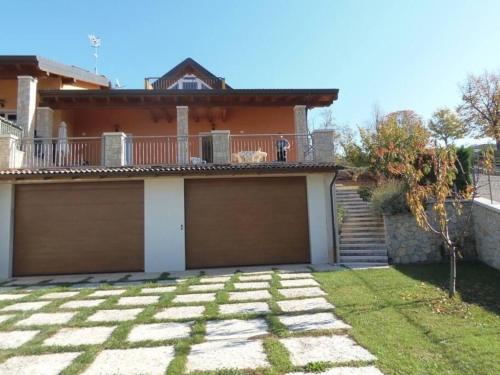 une maison avec deux portes de garage dans une cour dans l'établissement Ferienhaus für 10 Personen in San Zeno di Montagna, Gardasee Ostufer Gardasee, à San Zeno di Montagna