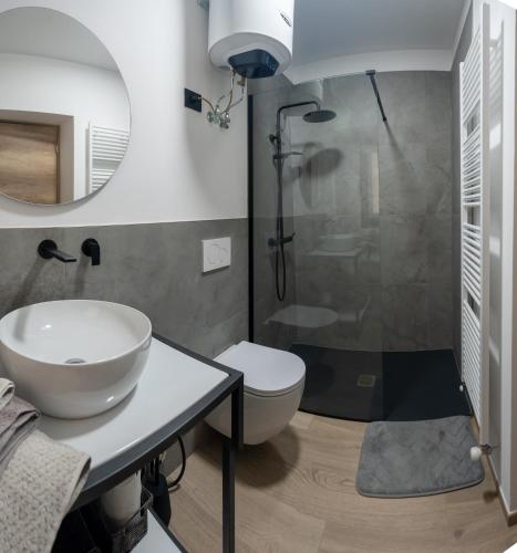 a bathroom with a sink and a toilet and a mirror at Ottavio's House, 10min from Maggiore Lake in Ornavasso
