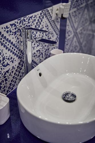 a white sink in a bathroom with a patterned wall at Trinacria Caccamo - Luxury Rooms in Caccamo