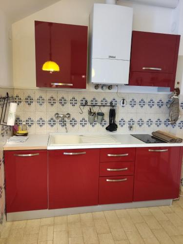 cocina con armarios rojos y fregadero blanco en mare e verde a celle ligure, en Celle Ligure