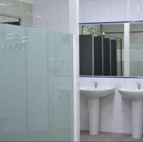 uma casa de banho com 2 lavatórios e um espelho em Albergue Augas Quentes em Ourense