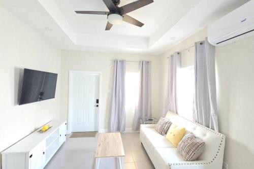 a living room with a white couch and a ceiling fan at Ocean Blue Villa in Lucea in Point