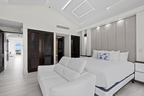 a white bedroom with a white bed and a couch at Las Casitas Village at El Conquistador in Fajardo