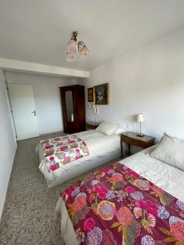 two beds in a hotel room with a colorful blanket at El Violetu in Cue