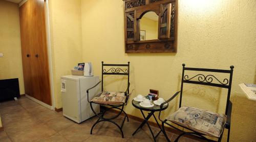 a kitchen with two chairs and a small refrigerator at Pilgrim's Rest - Descanso del Peregrino in Chacras de Coria