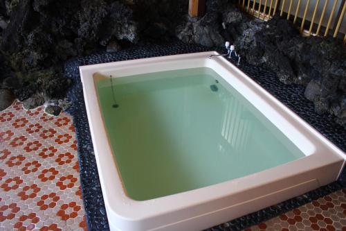 a large bath tub sitting on a tiled floor at Kinokuniya Ryokan in Fujisawa