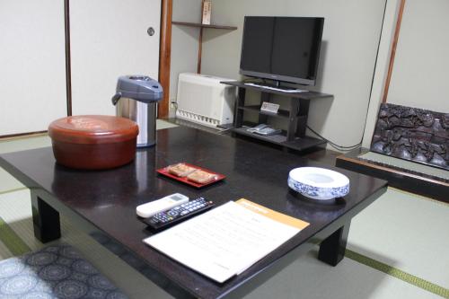 a coffee table with a tv and remote controls on it at Kinokuniya Ryokan in Fujisawa