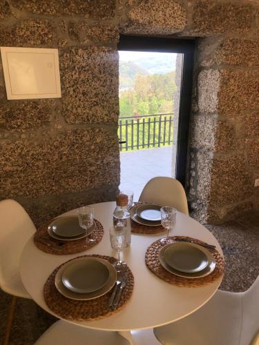 einen Tisch mit Stühlen und Tellern sowie ein Fenster in der Unterkunft Sobreiro Valley - Casa Isabel in Vieira do Minho