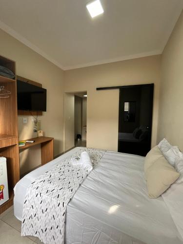 a large white bed in a room with a kitchen at Casa Lua Flat in Brumadinho