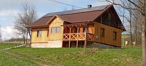 uma casa de madeira com um telhado de gambrel num campo em Miodowe wzgórze em Jastrzębia