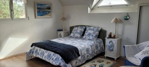 ein Schlafzimmer mit einem Bett mit blauer Decke und einem Fenster in der Unterkunft Maison Colleville-Montgomery - Bord de mer in Colleville-Montgomery