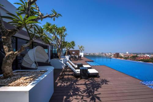 un balcón con bancos y una piscina en un edificio en Maline Exclusive Serviced Apartments en Phnom Penh