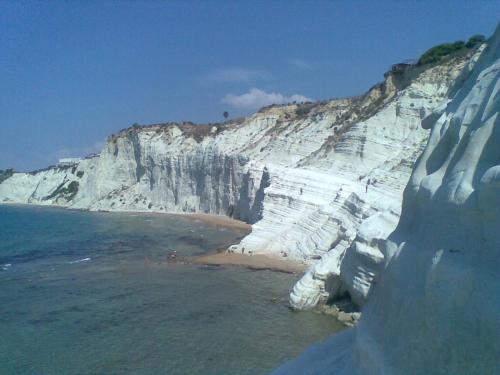 a white cliff next to a beach next to the water at M'arriposu in Realmonte
