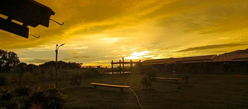 a sunset with a group of benches in a field at Pousada Horizonte por do sol in Nobres