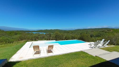 a swimming pool with three chairs and a table at Casa Paradiso in Coronel Moldes