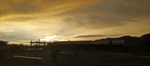 einen Sonnenuntergang über einem Gebäude auf einem Feld mit dem Himmel in der Unterkunft Pousada Horizonte por do sol in Nobres