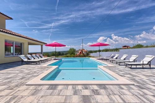 - une piscine avec des chaises et des parasols sur une terrasse dans l'établissement Ferienhaus mit Privatpool für 12 Personen ca 350 qm in Barban, Istrien Bucht von Raša, à Barban