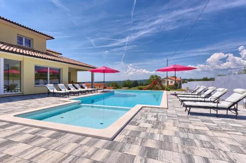 - une piscine avec des chaises et des parasols sur une terrasse dans l'établissement Ferienhaus mit Privatpool für 12 Personen ca 350 qm in Barban, Istrien Bucht von Raša, à Barban