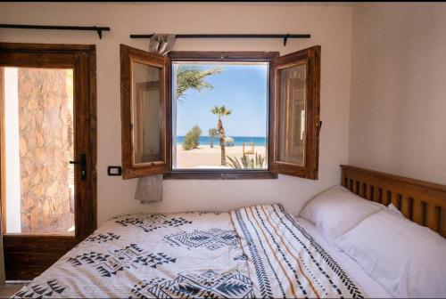 a bedroom with a bed and a window with a view of the beach at Sukoon Camp in Nuweiba
