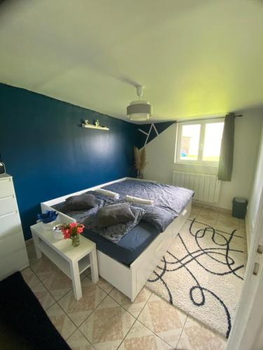a bedroom with a bed with a blue wall at Chambre dans maison de campagne in Vascoeuil