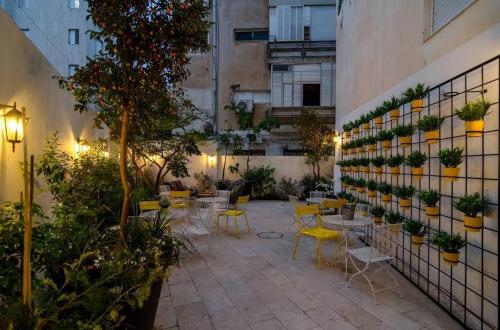 einen Innenhof mit Tischen, Stühlen und Pflanzen in der Unterkunft Just Like Hotel in Tel Aviv