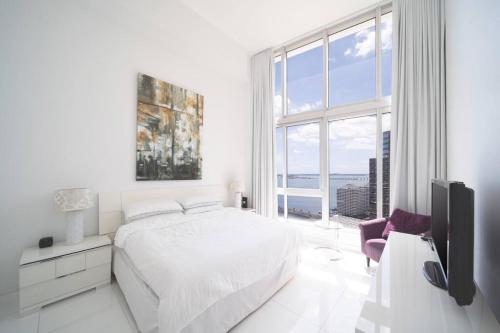 a white bedroom with a bed and a large window at Stunning Brickell Luxury Condo in Miami