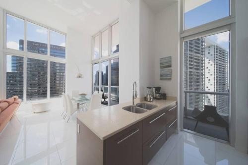 a white kitchen with a sink and large windows at Stunning Brickell Luxury Condo in Miami