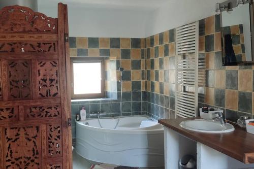 La salle de bains est pourvue d'une baignoire, de 2 lavabos et d'une fenêtre. dans l'établissement Retrouvez votre famille ou vos amis au calme, à Aigueperse