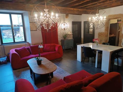 un salon avec des canapés rouges et une table dans l'établissement Retrouvez votre famille ou vos amis au calme, à Aigueperse